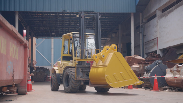 forklift carrying the large excavator bucket